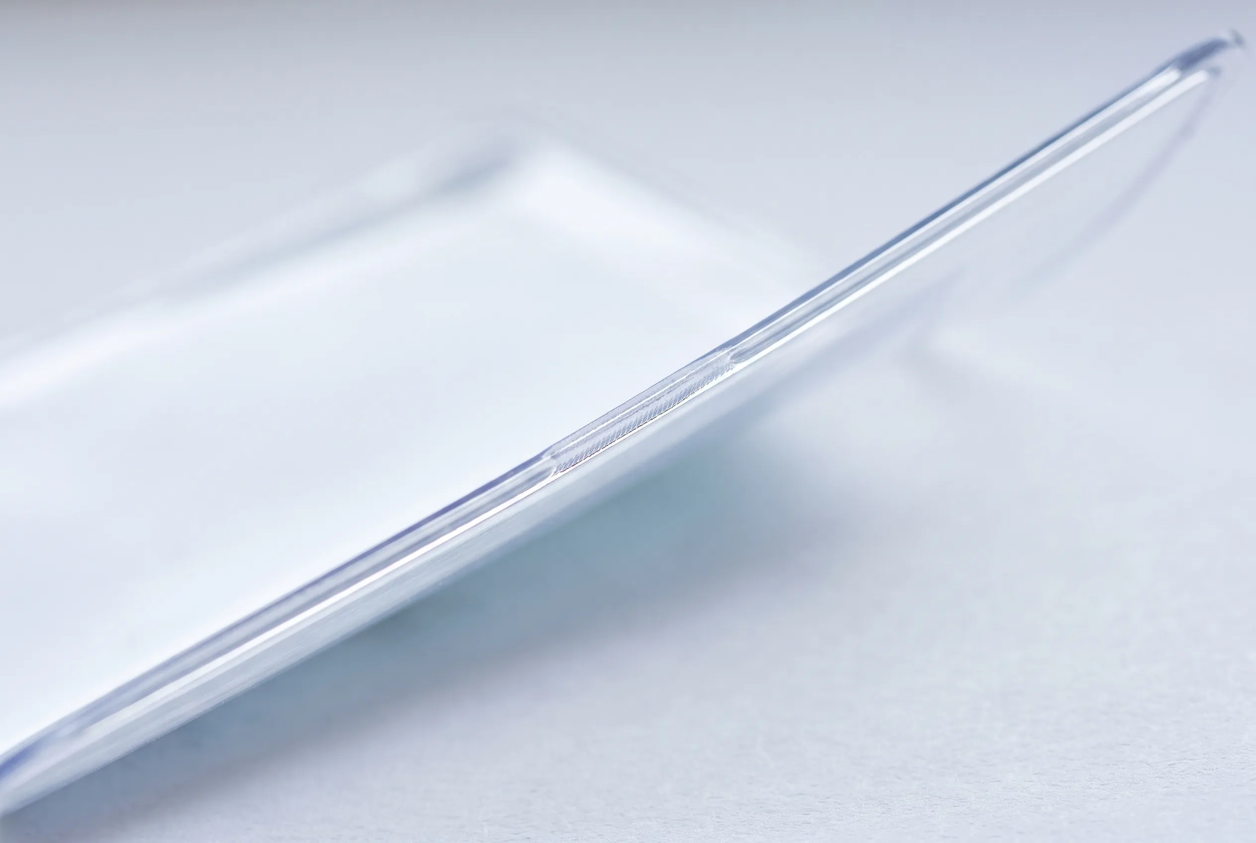 Macro view along the sealed edge of a clear PVC pouch, with light transmitting through the material.