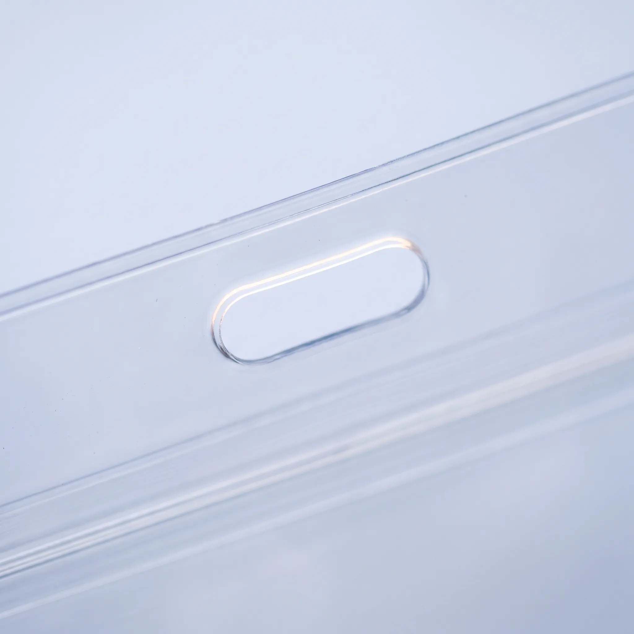 Macro view of a cleanly punched oval lanyard slot in the top edge of a clear PVC pouch.